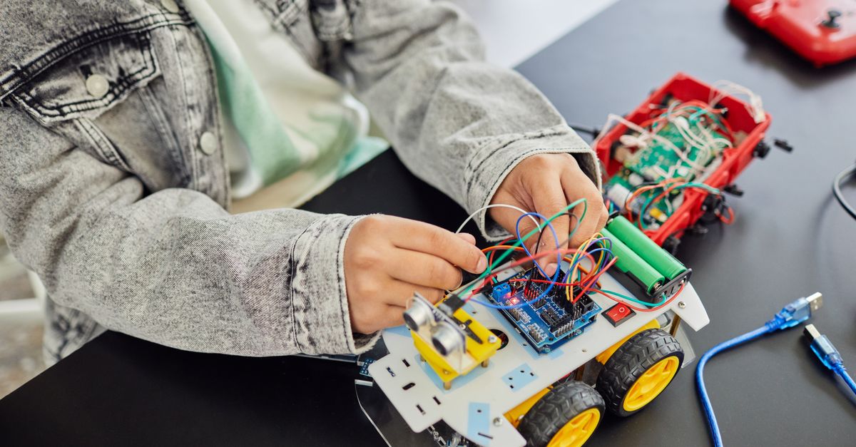 Young student assembling a toy car with electronic components, focusing on STEM education.